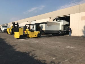 A large yellow forklift parked in front of a white building.