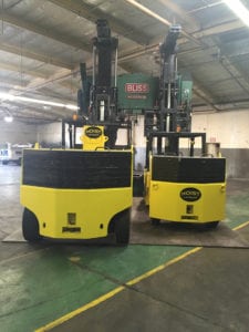 Two large yellow forklifts in a warehouse.