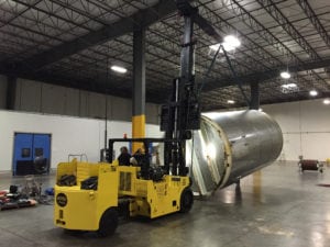 A large metal tank being lifted by a forklift.