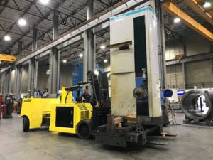 A yellow forklift is parked in front of a large machine.