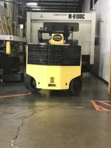 A yellow and black forklift parked in a warehouse.