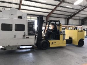 A man driving a forklift in a warehouse.