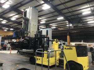 A large yellow truck in a warehouse with machinery.