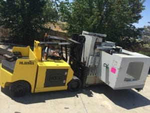 A forklift is shown next to an old refrigerator.