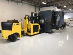 A yellow forklift parked in front of a machine.