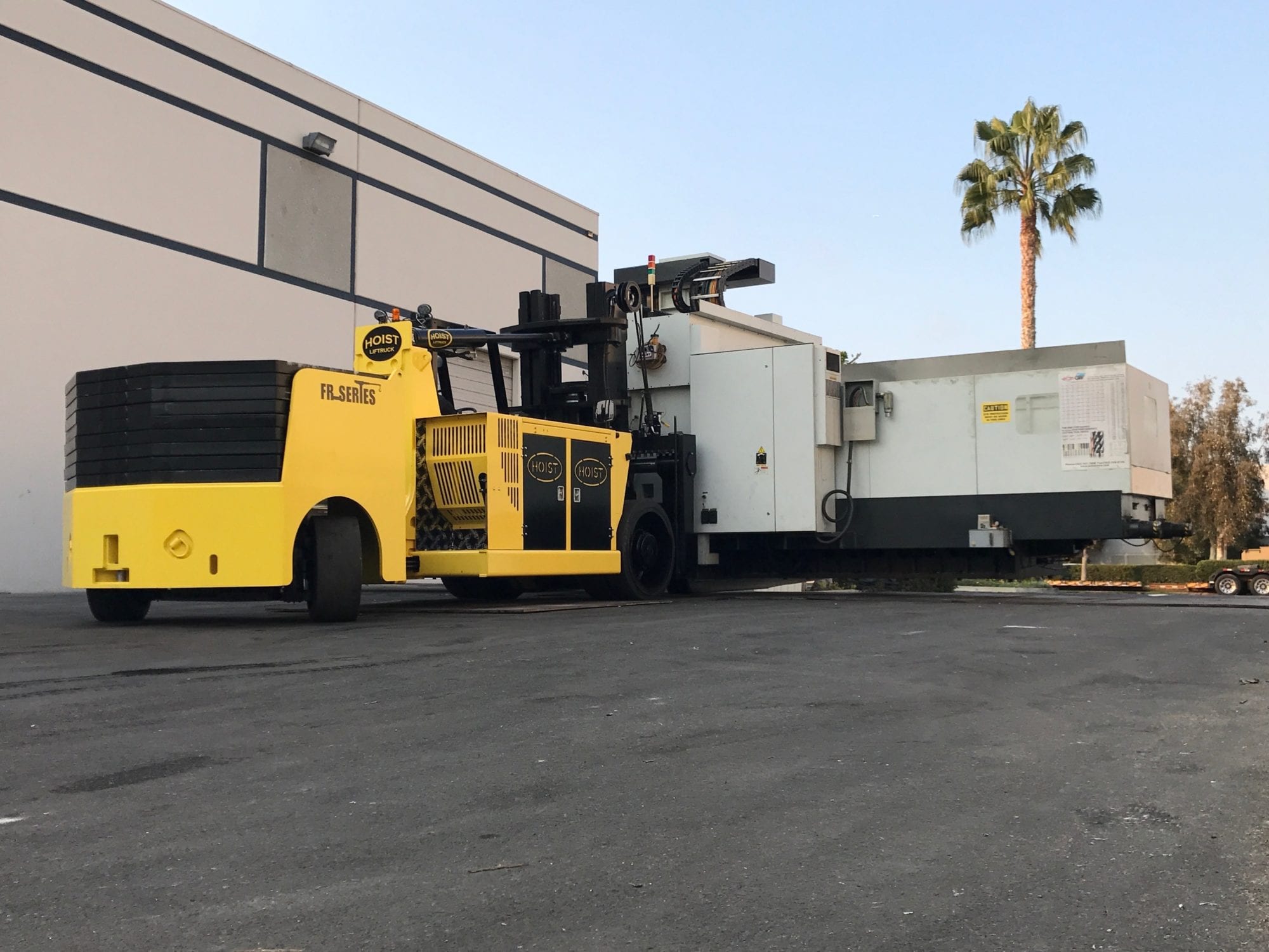 A yellow forklift is parked in front of a building.