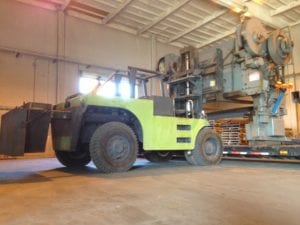 A yellow forklift in a warehouse with other machinery.