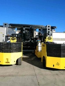 Two yellow and black forklifts in a parking lot.