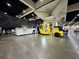 Yellow forklift beside trailer in warehouse setting.