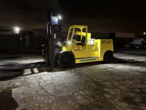 Yellow forklift operating at night outdoors.