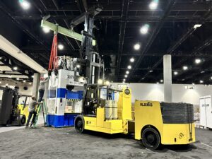 Forklift lifting heavy machinery in exhibition hall.