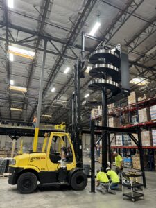 Forklift and workers in large warehouse.