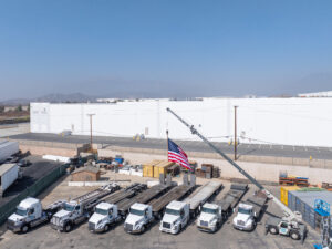 Trucks parked near American flag and crane.