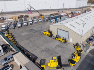 Industrial yard with trucks and yellow equipment.