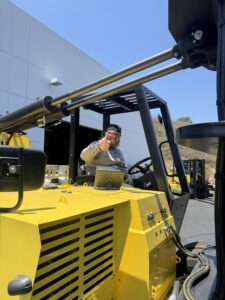Man giving thumbs up from yellow forklift.